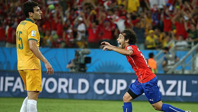 Mile Jedinak watches as Chile\'s Jorge Valdivia scores the second goal