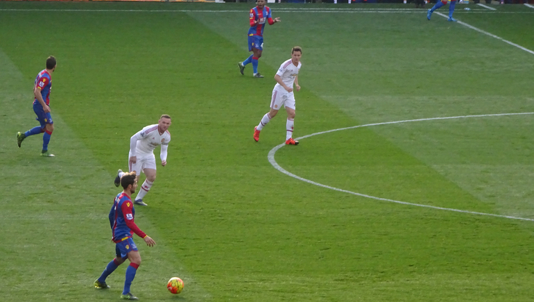 Palace's French playmaker Yohan Cabaye runs at the Man U goal area, closely watched by Wayne Rooney.