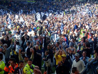 A large gathering of West Brom supporters applaud the Palace supporters.